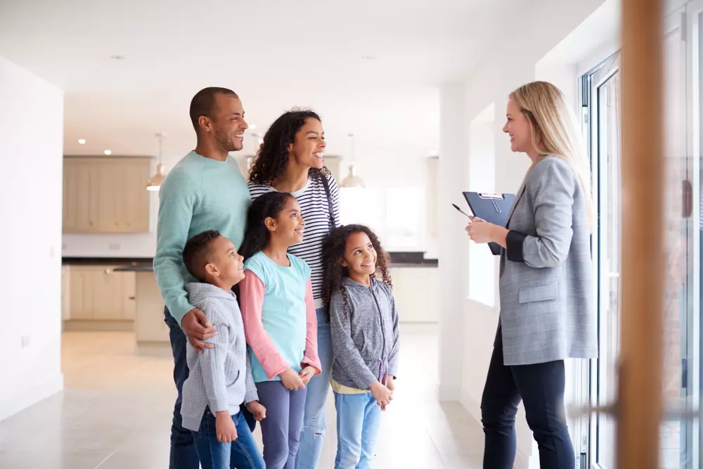 A family speaking with a female agent in a new home